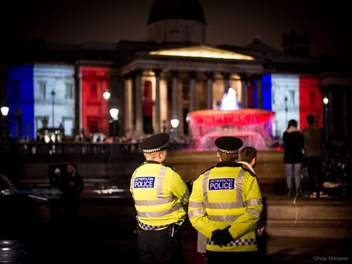 London, UK. 14 November, 2015. Metropolitan Police Officers stand guard as thousands gather in Trafalgar Square for a candlelit vigil in solidarity with the victims of last night's terrorists attacks in Paris.